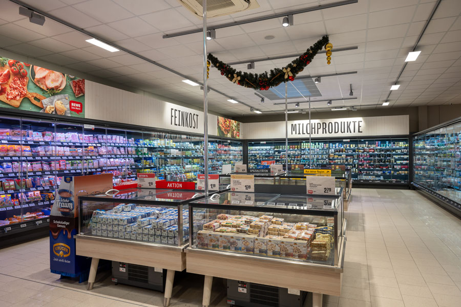 Kühlregale mit Feinkost und Milchprodukten in einem Supermarkt.